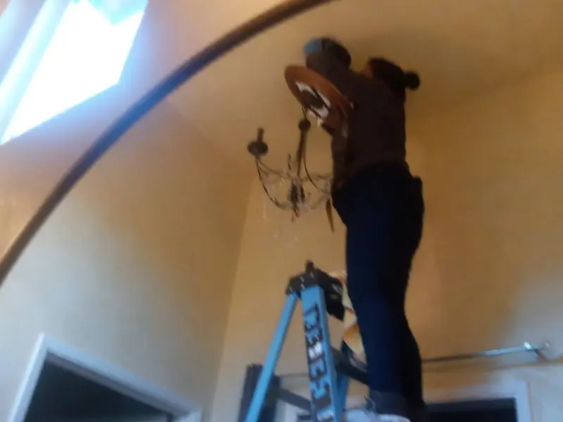Electrician installing a chandelier in a Jefferson Hills residence